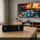 Amazon Fire TV Alexa Voice Remote on living room coffee table with Smart TV streaming home screen in background