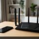 Black multi-antenna wireless Netgear router on an oak desk next to a phone