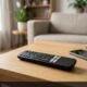 Black streaming media remote control resting on an oak table next to a smartphone
