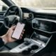 Car infotainment touchscreen displaying Bluetooth pairing failed screen while driver holds smartphone