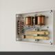 Open mechanical doorbell chime box mounted on wall showing electromagnetic coils and wiring